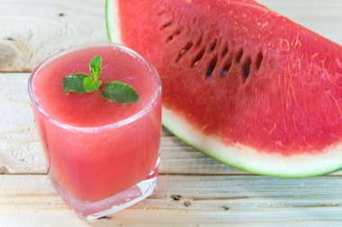 Ahşap masa üzerinde bardak taze karpuz suyu ile nane yaprakları