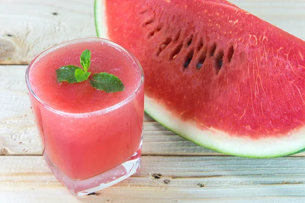 Bicchiere di succo d'anguria fresco con foglie di menta sul tavolo di legno — Foto Stock