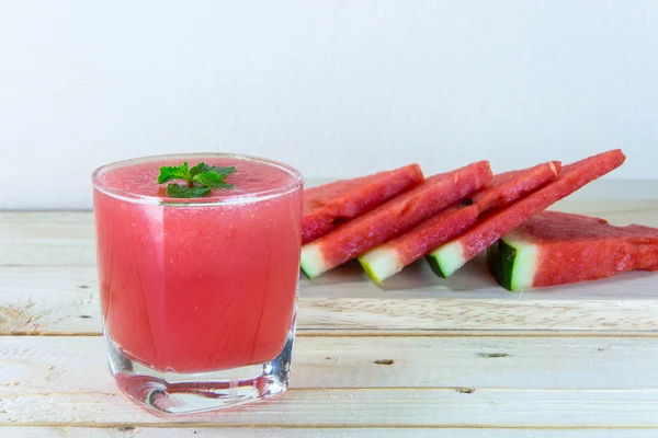 Watermeloen sap met munt verlaat en gesneden fruit op de houten b — Stockfoto