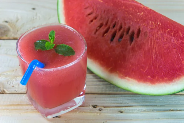 Bicchiere di succo d'anguria fresco con foglie di menta sul tavolo di legno Immagine Stock