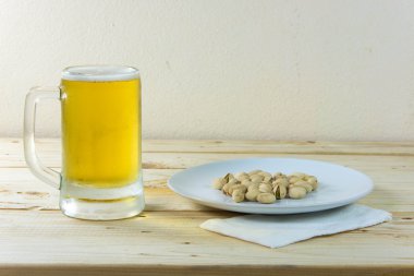 Antep fıstığı ve ahşap masa b bir bardak bira ile natürmort