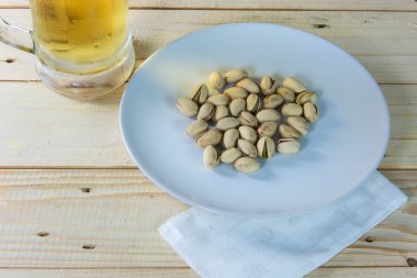 Antep fıstığı ve ahşap masa b bir bardak bira ile natürmort