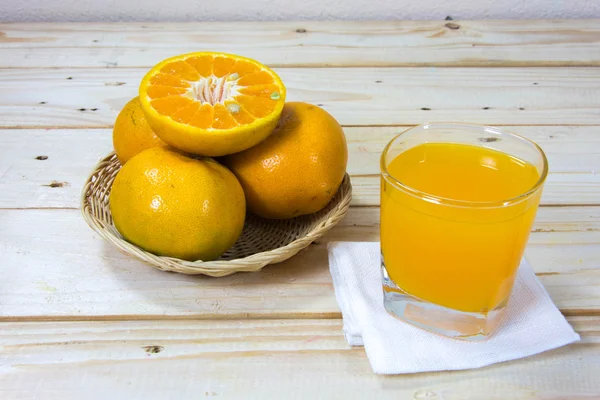 Glas leckerer Orangensaft und Orangenscheiben auf Holz-T — Stockfoto
