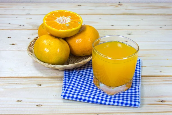 Glass of delicious orange juice and slices of orange on wooden t — Stock Photo, Image