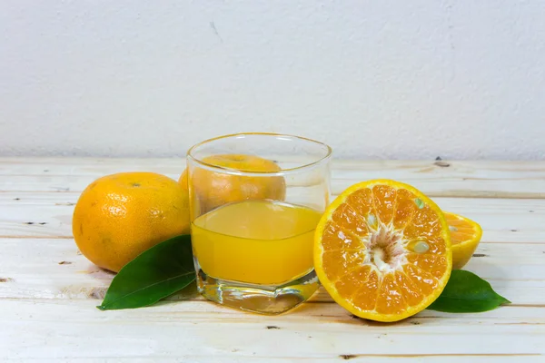 Glass of delicious orange juice and slices of orange on wooden t — Stock Photo, Image