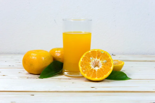 Glas leckerer Orangensaft und Orangenscheiben auf Holz-T — Stockfoto