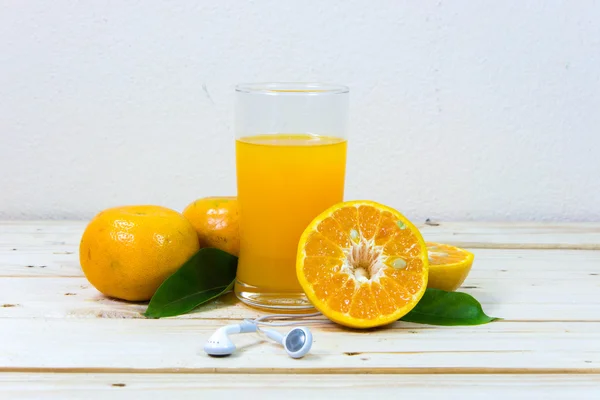 Copo de suco de laranja delicioso e fatias de laranja em t de madeira — Fotografia de Stock