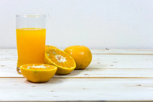 Склянка смачного апельсинового соку та скибочки апельсина на дерев'яній т — стокове фото