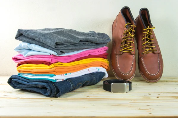 Still life with plaid shirt, jeans, brown boots on wooden table — Stock Photo, Image