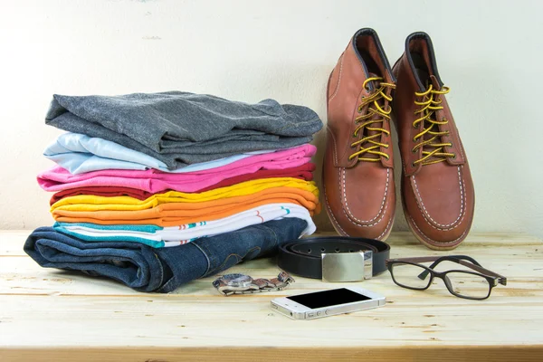 Still life with plaid shirt, jeans, brown boots on wooden table — Stock Photo, Image