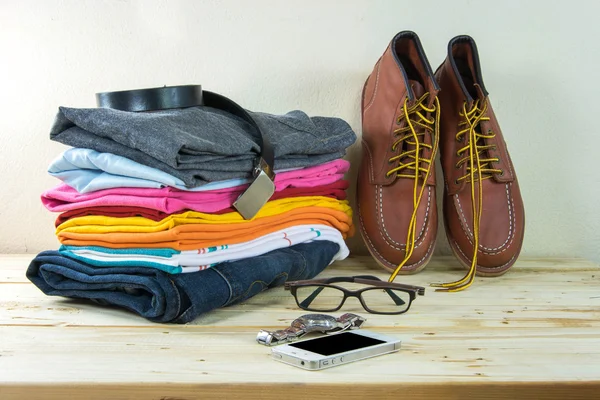 Still life with plaid shirt, jeans, brown boots on wooden table — Stock Photo, Image