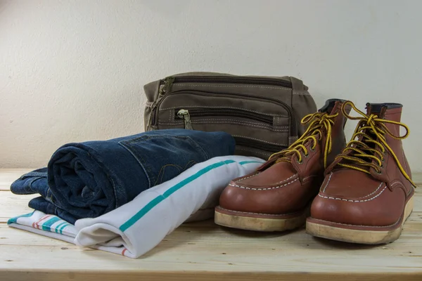 Still life with plaid shirt, jeans, brown boots and bag on woode — Stock Photo, Image