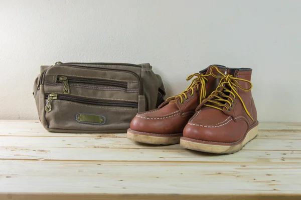 Still life with boots and bag on wooden table background. — Stock Photo, Image