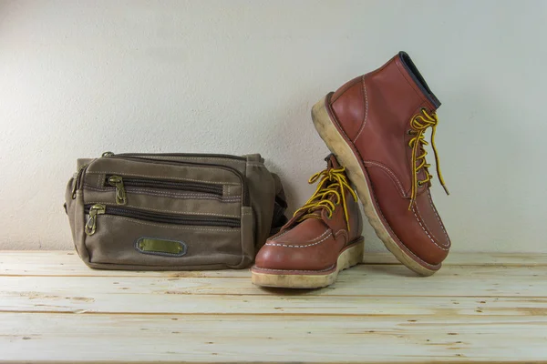 Still life with boots and bag on wooden table background. — Stock Photo, Image