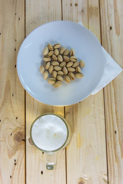 Antep fıstığı ve ahşap masa b bir bardak bira ile natürmort