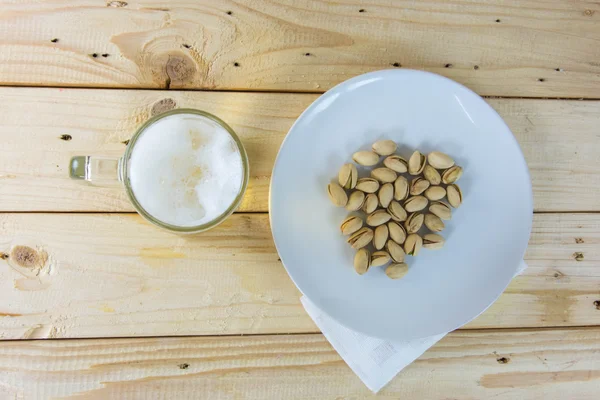 Still life with pistachios and beer in a glass on wooden table b — Stock Photo, Image