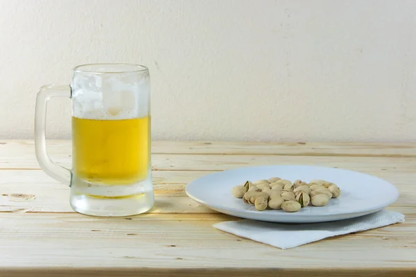 Natureza morta com pistácios e cerveja em um copo na mesa de madeira b — Fotografia de Stock