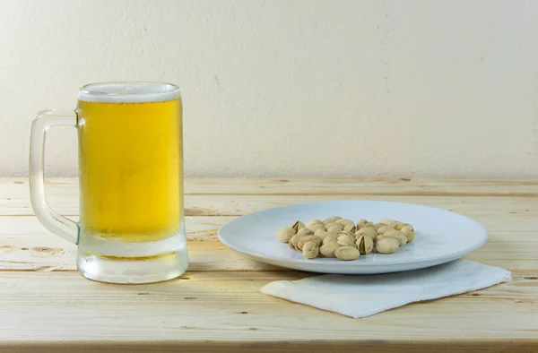 Natureza morta com pistácios e cerveja em um copo na mesa de madeira b — Fotografia de Stock