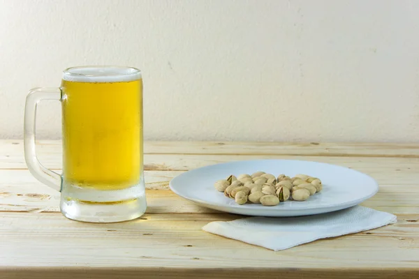 Martwa natura z pistacji i piwo w szklance na drewnianym stole b — Zdjęcie stockowe