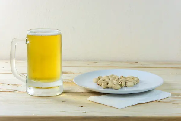 Stillleben mit Pistazien und Bier im Glas auf Holztisch — Stockfoto