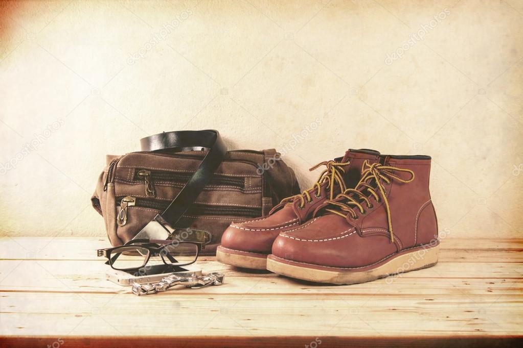 Still life with casual man, boots and bag on wooden table backgr