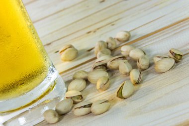 Antep fıstığı ve ahşap masa b bir bardak bira ile natürmort