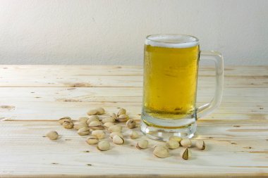Antep fıstığı ve ahşap masa b bir bardak bira ile natürmort