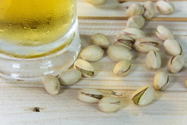 Stillleben mit Pistazien und Bier im Glas auf Holztisch — Stockfoto