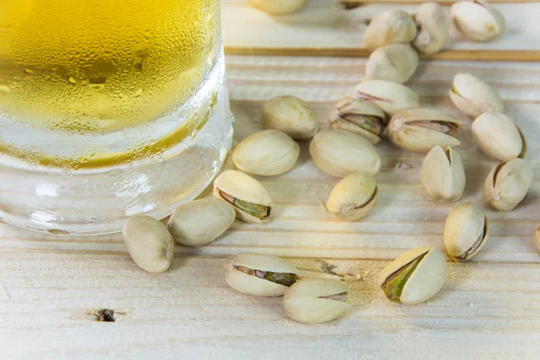 Natureza morta com pistácios e cerveja em um copo na mesa de madeira b — Fotografia de Stock