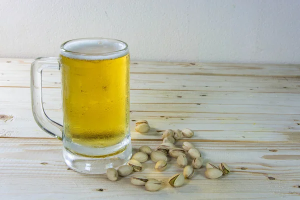 Stillleben mit Pistazien und Bier im Glas auf Holztisch — Stockfoto