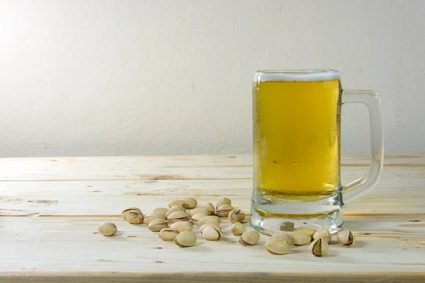 Natureza morta com pistácios e cerveja em um copo na mesa de madeira b — Fotografia de Stock