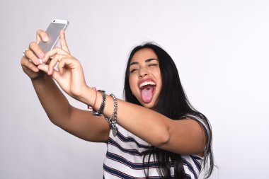 Genç bir kadın akıllı telefonuyla selfie çekiyor.