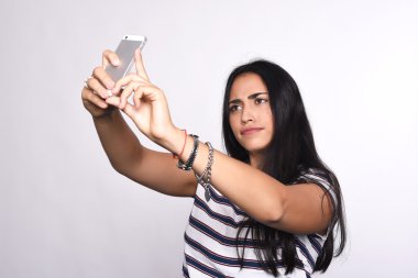 Genç bir kadın akıllı telefonuyla selfie çekiyor.
