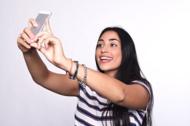 Genç bir kadın akıllı telefonuyla selfie çekiyor.