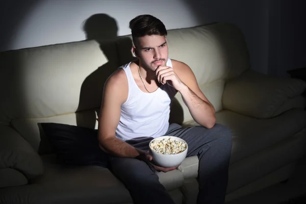 Jeune bel homme mangeant du pop-corn. Intérieur . — Photo