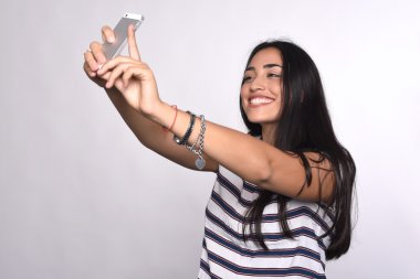 Genç bir kadın akıllı telefonuyla selfie çekiyor.