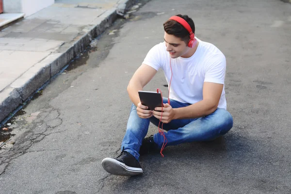 Hombre latino usando una tableta con auriculares —  Fotos de Stock