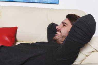mutlu genç adam kanepede yatan ve rahatlatıcı