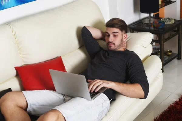 Jovem homem bonito usando seu laptop — Fotografia de Stock