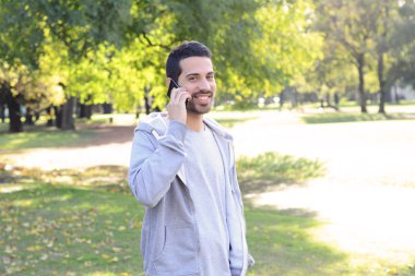 Telefonda konuşan genç adam. Açık havada.