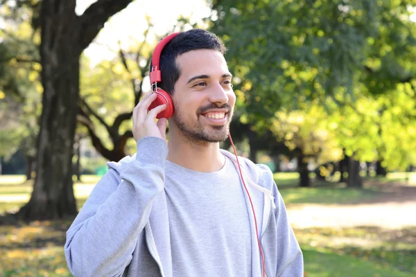 Giovane che ascolta musica con le cuffie nel parco . — Foto Stock