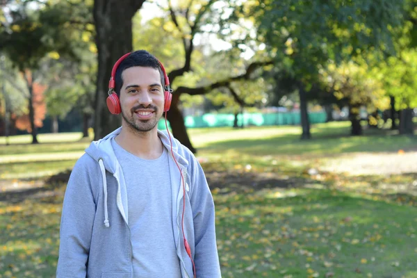 Giovane che ascolta musica con le cuffie nel parco . — Foto Stock