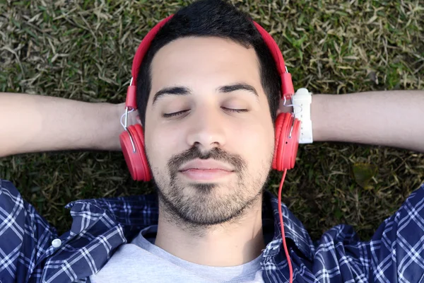 Jongeman, luisteren naar muziek met koptelefoon in park. — Stockfoto