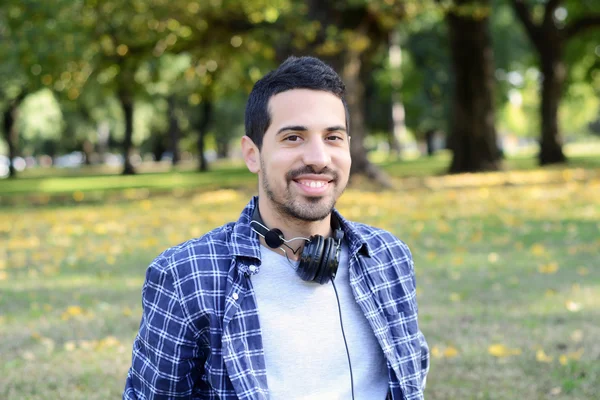 Genç adam bir parkta kulaklıklarla.