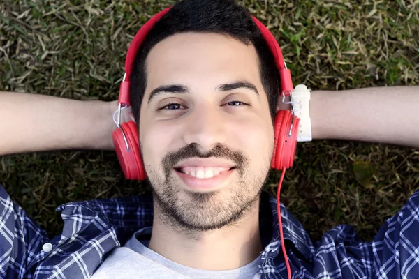 Молодой человек слушает музыку в наушниках в парке . — стоковое фото