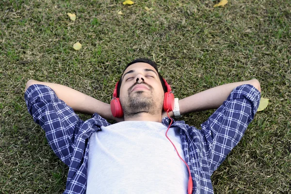 Giovane che ascolta musica con le cuffie nel parco . — Foto Stock