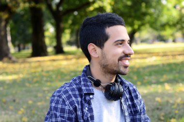 Genç adam bir parkta kulaklıklarla.