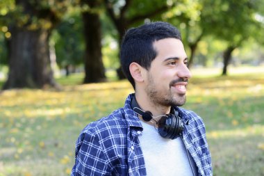 Genç adam bir parkta kulaklıklarla.