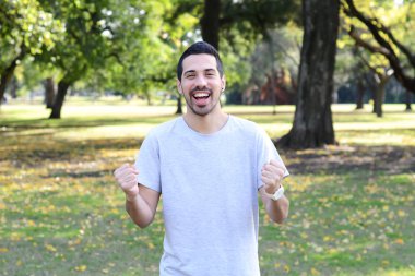 Başarı jest bir parkta yapan genç latin erkek.