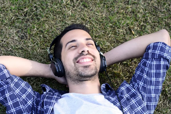 Giovane che ascolta musica con le cuffie nel parco . — Foto Stock